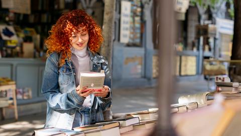 Eine junge Frau entdeckt ein Buch im Antiquariat.