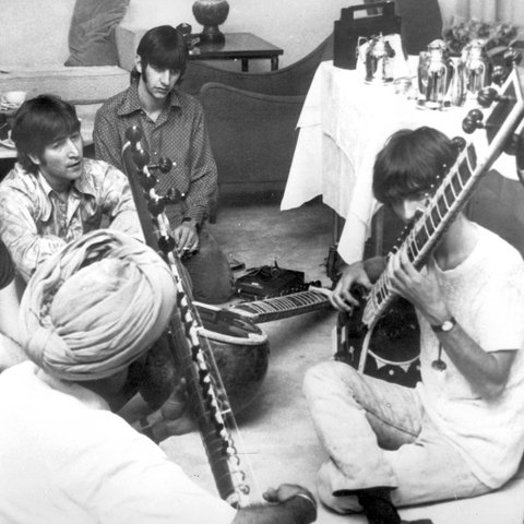 George Harrison nimmt Sitar-Unterricht in Neu Delhi, während Paul McCartney, John Lennon und Ringo Starr zuschauen.