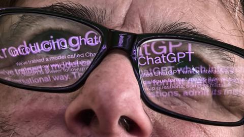 Der Schriftzug "Chat GPT" spiegelt sich in einer Brille.