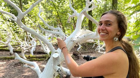 Die Künstlerin Kim Rathnau bei der Arbeit an ihrem Werk "Forest Bleaching" auf dem Waldkunstpafd in Darmstadt 2024