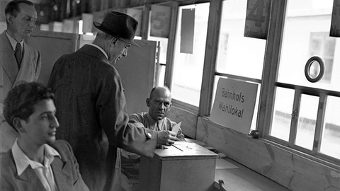 Ein Reisender gibt am 14. August 1949 in einem Wahllokal im Frankfurter Hauptbahnhof seine Stimme ab. An diesem Tag fanden in der Bundesrepublik die Wahlen zum ersten Deutschen Bundestag statt.