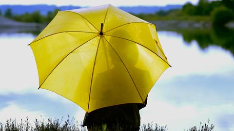 Frau mit Regenschirm am Ufer