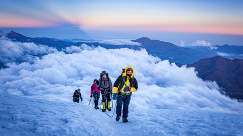 Bergsteiger erreichen vor Sonnenaufgang den Gipfel.