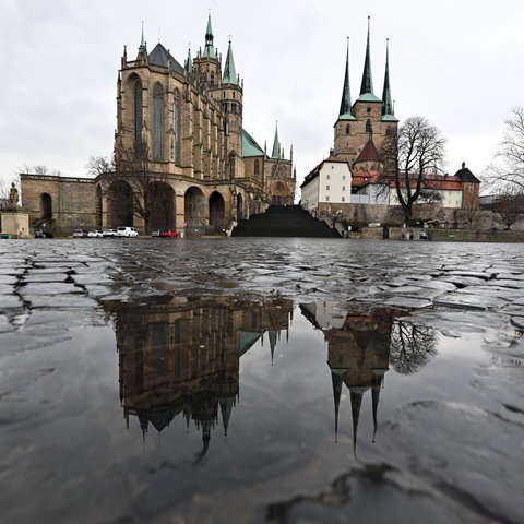 Der katholische Mariendom und die Severikirche spiegeln sich auf dem nassen Pflaster des Domplatzes.