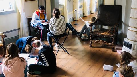 Schüler sitzen im Museum auf dem Boden und Schreiben